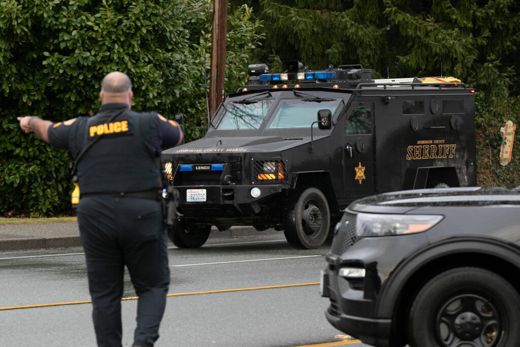 An Everett Police officer directs an armored vehicle from the Snohomish County Sheriff’s Department during a standoff related to a shooting at The Bluffs Apartments on West Casino Road on Monday, Jan. 22, 2024, in Everett, Washington. (Ryan Berry / The Herald) 